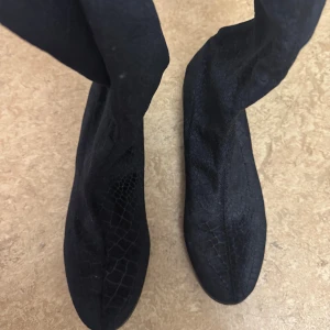 Svarta höga boots med snörning - Säljer ett par svarta boots med coolt ormskinnsmönster och snörning upptill. Storlek 38, aldrig använt.  