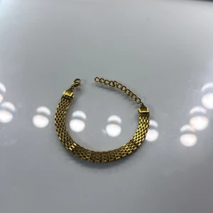 Guldigt kedjearmband med justerbar länk - Snyggt armband i guldig metall med bred, platt kedja och justerbar länk för perfekt passform. Armbandet har ett klassiskt och stilrent utseende med glänsande yta och smidig karbinhake. Perfekt accessoar för att lyfta din outfit.