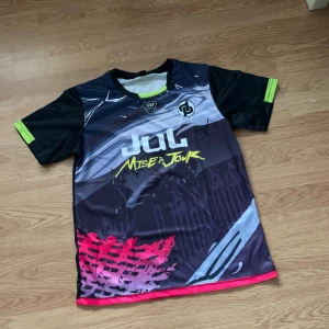 Färgstark Jul fotbollströja - Unik fotbollströja från Jul med coolt grafiskt tryck i svart, grått, vitt och neonfärger. Kortärmad modell i lätt och glansigt material, perfekt för match eller träning. Snygga detaljer med loggor och text både fram och bak.