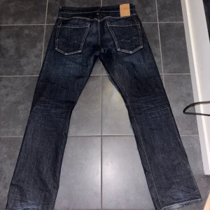 Replay mörkblå jeans straight fit - Snygga mörkblå jeans från Replay med klassisk femficksdesign och kontrastsömmar. Modellen har rak passform och normal midja. Materialet är slitstarkt jeans och Replay-loggan syns på fickan fram. Perfekt för dig som gillar stilrena och tidlösa jeans.