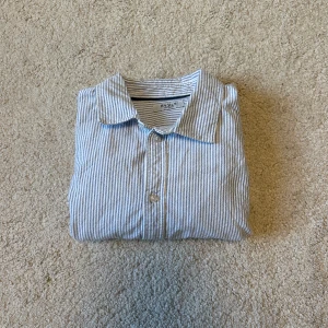 Randig skjorta från RYVLS Stockholm - Klassisk skjorta från RYVLS Stockholm i vitt och blått med smala ränder. Skjortan är köpt för ungefär 2 månader sedan men använd max 4 gånger. Den är i väldigt fint skick och passar dig som bär storlek S. Nypris på denna skjorta är 400kr mitt pris är endast 199kr, hör av er vid intresse!