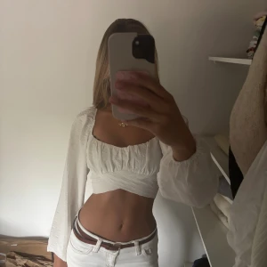 Vit topp  - Säljer en supersöt vi topp från Gina Tricot. Står storlek 32, men skulle säga att den passar mellan xs till M eftersom man spänner in den själv med rosetten där bak. Den har fått lite missfärgning vid kanten på framsidan, men är knappt märkbart när man har på sig den. Priset går alltid att diskutera och tveka inte att höra av dig vid frågor❤️