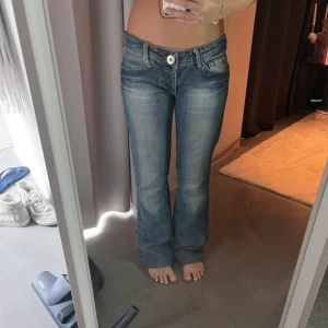 bootcut jeans låg midja - Snygga blå jeans från Dolce & Gabbana med låg midja och bootcut passform. Klassisk femficksmodell med vit knapp framtill och slitningar för en cool look. Jeansen är i mjukt denim-material och har en lätt tvättad finish. Midja: 37 längd: 80