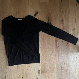Svart kofta - Svart kofta med V-ringning. Köptes secondhand så vet ej hur mycket den använts men inga defekter. Säljer den då den är lite stor och jag därför aldrig använd den. Storlek L men passar även dig med mindre storlek om du vill ha en mer ”relaxed” passform.