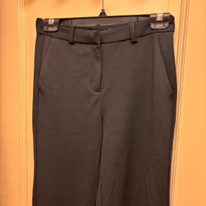 Svarta kostymbyxor från Vero Moda - Snygga svarta kostymbyxor från Vero Moda. Byxorna har diskreta fickor fram och är tillverkade i ett mjukt material som ger en stilren look. Skulle säga att de är som en 36/38.