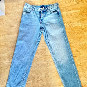 Ljusblå relaxed fit jeans från H&M - Säljer ett par ljusblå jeans från H&M i relaxed fit med justerbar midja. Klassisk femficksmodell med dragkedja och knapp. Jeansen har raka ben och är tillverkade i bomull. Perfekta för en chill och avslappnad stil.