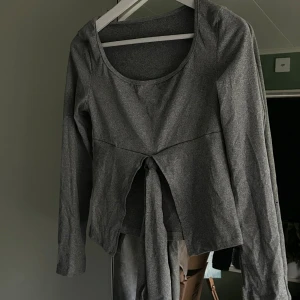 Grå långärmad knyttopp - Snygg grå långärmad topp med bred rund halsringning och knyt framtill i midjan. Modellen är figurnära, mjukt och stretchig🫶🏻