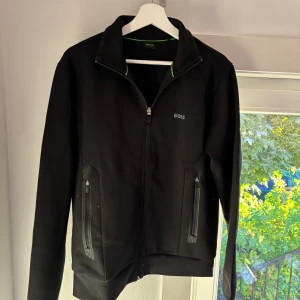 Svart vindjacka från BOSS - Svart BOSS zip up, nästan oanvänd, säljs just nu på boozt på rea för 1200kr du får exakt samma tröja här för flera hundra kr billigare så passa på!