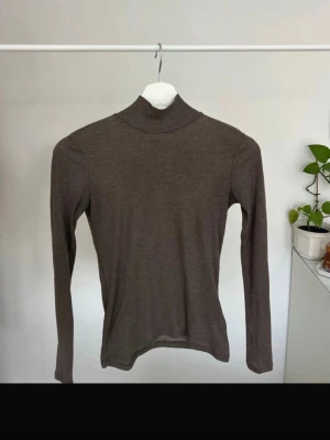 Brun polotopp  - Enkel och stilren brun polotopp med lång ärm från hm, Stl xs