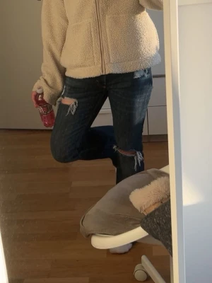 Mörkblå bootcut jeans med slitningar - Säljer ett par mörkblå jeans med bootcut passform och slitna detaljer vid knäna och låren. Från weekday, klippt hålen själv. Storlek 28/32. De är stora i midjan på mig så har en tråd som jag kan knyta i byxorna (skriv för bild) som enkelt går att ta bort utan att de ändrar hur byxorna ser ut. Skriv för bilder och buda gärna! 