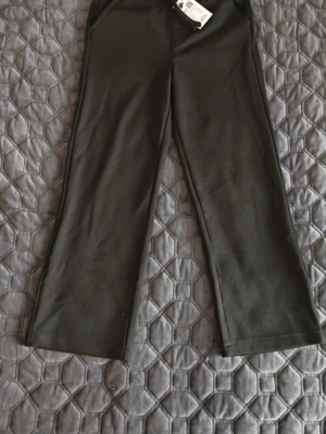 Barn byxor i str 130 från lager 157 - Svarta barn byxor i str 130 från 157 med bekväm dragsko i midjan. Byxorna har raka ben och är gjorda i en mjuk mix av polyester, viskos och elastan. Perfekta för chill dagar och har en enkel, stilren look som funkar till det mesta.