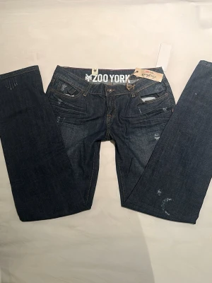 Zoo York mörkblå straight  jeans  - Mörkblå jeans från Zoo York med coola slitningar och detaljer på både fram- och baksida. Innerbenslängden: 78 cm, midjemåttet: 38 cm 