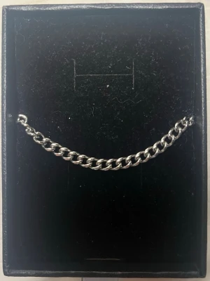 Silvrigt kedjearmband från Lyxery by Sweden - Snyggt och stilrent armband i silver från Lyxery by Sweden. Helt oanvänt säljer för det var lite för litet. Kedjan är 17 cm lång och 4 mm bred. Orginalpris 449 kr. Kedjan är i kirurgiskt stål.