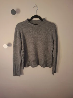 Grå stickad tröja från Monki - Säljer en grå stickad tröja från Monki i storlek S. Tröjan har en rund halsringning, ribbade muddar vid ärmslut och nederkant.💕 