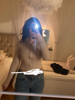 Beige ribbad kofta med krage - En fin beige koft/tröja med ribbad material och krage vid halsen! Den har dragkedja.