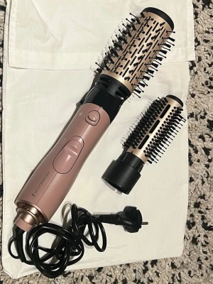 Värmeborste från Remington  - Bilderna visar en hårstyler från Remington med två utbytbara borstar. Produkten är rosa och svart med metalliska detaljer och är avsedd för hårstyling. Nypris 300 säljer för 200 då den aldrig är andvänd eftersom jag redan har en! Funkar jättebra, jag har testat alla funktioner för att se att de går och det ser normalt ut, båda borstarna sätter man på och byter ut när man vill!☺️