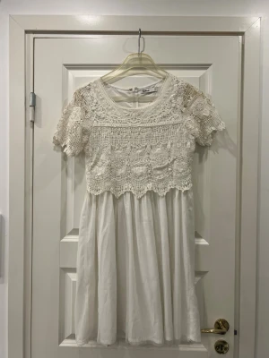 Vit spetsklänning från Cubus - Säljer en söt vit kortklänning från Cubus i storlek 38. Klänningen har ett överdel i spets med blommigt mönster och korta ärmar, samt rund halsringning. Kjoldelen är i mjukt tyg och klänningen har dragkedja i ryggen. Perfekt för sommarens alla tillfällen!