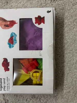 Lera med tillbehör - En förpackning med lek- och formsand samt tillhörande formar och verktyg. Skicka för fler bilder.