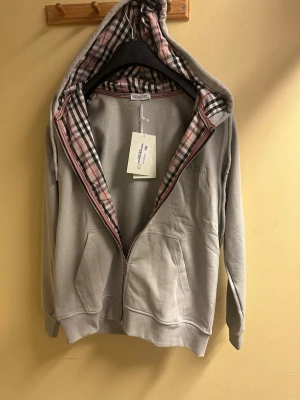 Grå Burberry Hoodie. M - Helt ny, aldrig använd hoodie från Burberry. Färg grå och storlek finns S, M