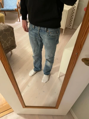 Levi's 501 jeans - Säljer ett par klassiska Levi's 501 jeans i ljusblå tvätt med raka ben och normal passform. Jeansen har fem fickor, knappgylf och den ikoniska läderpatchen bak i midjan. Materialet är slitstarkt bomullsjeans och modellen har en tidlös look.