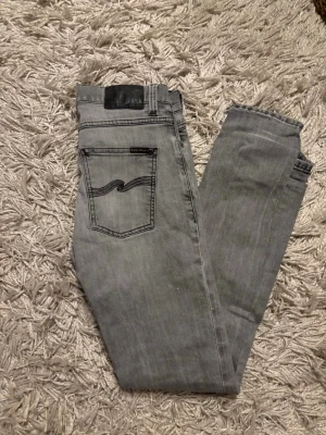  Nudie Jeans - Snyggas grå jeans från Nudie Jeans. Osäker på vilken modell dessa är men dom är väldigt lika dondup George. Väldigt gott skick utöver det lilla hålet i skrevet som jag inte hunnit laga men som man enkelt kan fixa.