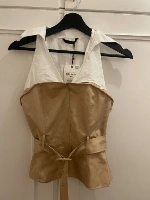 Beige och vit korsettopp med bälte - Super snygg, aldrig använd. Har lite smink fläckar men som inte synd när man har på sig den, och går med största sannolikhet bort i tvätten. 