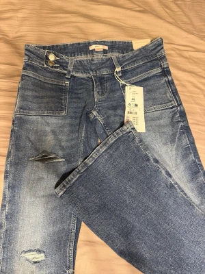 Blå bootcut jeans med slitningar XS - Säljer ett par blå bootcut jeans från Gina Tricot i storlek XS. Helt oanvända med prislapp på, nypris 399kr. 