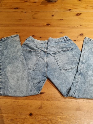 Acid wash cargopants i jeansmaterial - Säljer ett par ljusblå cargopants med acid wash-effekt. Byxorna har raka ben, flera fickor på sidorna och bak, samt hällor för bälte. Materialet är klassiskt jeans och de har en loose passform som ger en avslappnad vibe.