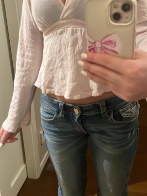 Ljusrosa omlottblus från Gina Tricot - Supersöt ljusrosa omlottblus från Gina Tricot i storlek XS. Blusen har v-ringning, långa ärmar med lite utsvängning och knytband i midjan. Den är tillverkad i ett tunt och lätt tyg. Perfekt att styla med jeans eller kjol. Den är endas använd ett fåtal gånger.