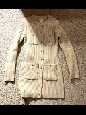 Stickad klänning - Stickad klänning från H&M i gräddvit färg med knappar.