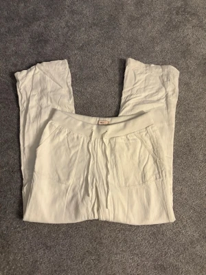 Vita linnebyxor från Nelly - Säljer ett par vita linnebyxor från Nelly i storlek S. Byxorna har bred resår i midjan med snörning och två stora fickor fram. Perfekta till sommaren. 