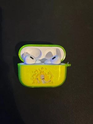 AirPods Pro med Rick and Morty-skal - Snygga AirPods Pro med aktiv brusreducering och trådlös laddning. Levereras med ett unikt Rick and Morty-skal i neonfärg som ger extra skydd och personlig stil. Hörlurarna och skalet ser ut att vara i gott skick utan synligt slitage eller repor.