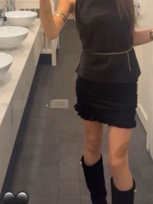 Svart kortkjol med volangkant - Använts en gång, gången på bilden. Säljer en svart kortkjol med volangkant längst ner. Kjolen har en tight passform och är perfekt för dig som gillar en stilren och trendig look. Materialet känns mjukt och följsamt mot kroppen. Passar dig som vill ha en enkel men snygg kjol till din outfit.