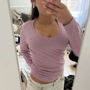 Ljuslila v-ringad tröja Tommy Hilfiger - Snygg ljuslila v-ringad tröja från Tommy Hilfiger i pima cotton blend. Klassisk passform med långa ärmar och diskret logga broderad på bröstet. Har några fläckar