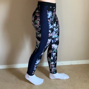 Blommiga leggings med mörkblå panel - Träningstights med blommönster, blå panel på sidan. Lätt noppriga