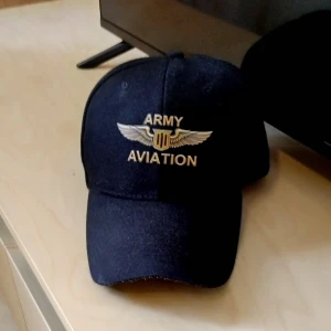 Mörkblå Army Aviation keps - Snygg mörkblå keps med broderad Army Aviation-logga och vingar framtill. Klassisk böjd skärm och justerbar passform. Perfekt för dig som gillar militärstil och vill sticka ut med en cool accessoar.