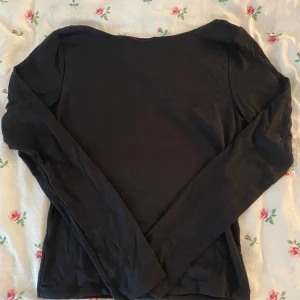 Svart långärmad topp Gina Tricot - Svart långärmad topp från Gina Tricot med djup, rundad urringning i ryggen. Enkel och stilren design i mjukt material, perfekt att matcha med jeans eller kjol. Snygg passform och klassisk look. Har aldrig använts!