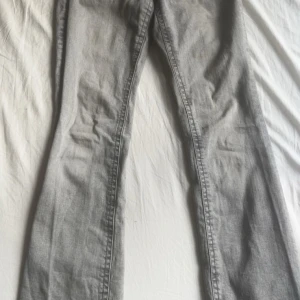 Grå bootcut jeans från Gina Tricot  - Snygga grå jeans från Gina tricot i bootcut-modell. Jeansen har coola fickdetaljer med lock och knapp bak, klassisk femficksdesign och är tillverkade i mjukt denimtyg. Perfekta för dig som gillar en avslappnad men trendig look.