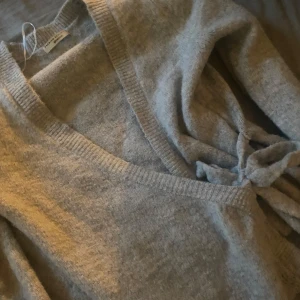 Knitted wrap cardigan - Mysig grå omlottkofta från gina tricot med knyt i sidan och v-ringad hals. Koftan är stickad och har långa ärmar, perfekt för lager-på-lager under kyliga dagar. Enkel att styla till både jeans och kjol. Som ny.                         SLUTSÅLD!!!
