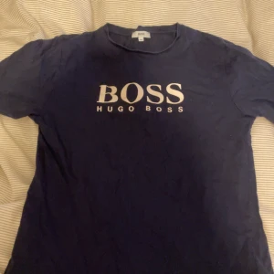 Mörkblå BOSS t-shirt med logga - Snygg mörkblå t-shirt från Hugo Boss med stor vit BOSS-logga framtill. Tröjan har inga täcken på användning.