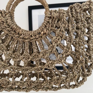 Farrow- Beige flätad handväska med rundade handtag - Från märket Farrow, tog bort bladet. Säljer en superfin beige handväska i flätad stil med stora runda handtag. Väskan har ett öppet, nätliknande mönster och är perfekt för sommarens alla äventyr. Den är lätt och har en unik boho-vibe som verkligen sticker ut.