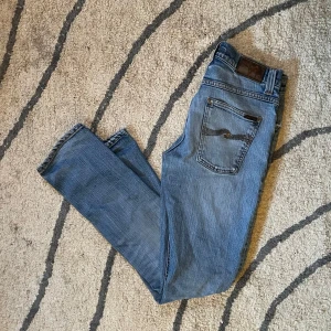 Nudie Jeans grim Tim  - Feta fadade ljusblå nudie jeans med slitningar. W30 L32 grim Tim
