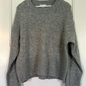 Grå stickad tröja - Mysig grå stickad tröja från Gina. Tröjan har en avslappnad passform och rund halsringning, perfekt för lager på lager under kyliga dagar. Den är använd endast ett fåtal gånger.🥰