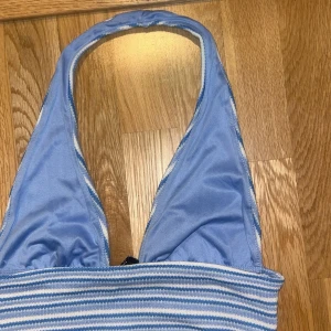 Blåvit randig bikiniöverdel H&M Divided - Supersöt  topp från H&M Divided i blått och vitt med smala ränder. Halterneck-modell med bred resår under bysten för extra stöd. Perfekt för varma sommar aktiviteter eller fest, och riktigt skön passform. Materialet är stretchigt och känns mjukt mot huden.