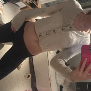 Beige stickad topp med knappar Zara - Superfin beige stickad topp från Zara med croppad passform och långa ärmar. Toppen har snygga knappar framtill och en mjuk, fluffig känsla. Perfekt att styla med höga jeans eller kjol för en trendig look.