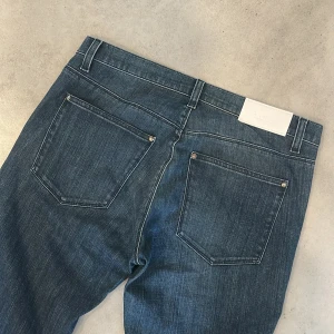 Blå raka jeans från Acne Studios - Snygga blå jeans från Acne Studios med klassisk femficksdesign och raka ben. Jeansen har en stilren look med mörk tvätt och subtila slitningar. Perfekta för dig som gillar en enkel och clean stil. Materialet är klassisk denim i bomull.