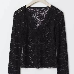 Svart spetsblus med v-ringning - Supersnygg svart topp med spets. V-ringad och långärmad, perfekt för att ge din outfit en extra edge. Blusen har en croppad passform och är gjord i mjuk polyester som känns skön mot huden. Pris kan diskuteras 