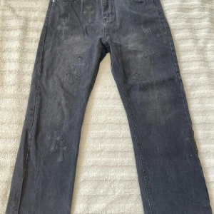 Chrome Hearts jeans - Grå Levi's 550 jeans i samarbete med Chrome Hearts, dekorerade med flera svarta läderkors på både fram- och baksida. Klassisk femficksmodell med raka ben och snygga detaljer i metall. Jeansen har en cool, något tvättad look och unika detaljer som sticker ut. ❗️Pris kan diskuteras❗️ Kontakta mig gärna inom Frågor om passform, Eller bara extra bilder🙌