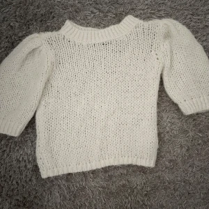 Vit stickad tröja från Vero Moda - Säljer en fluffig och mysig vit stickad tröja från Vero Moda i storlek XS. Tröjan har rund hals, puffiga trekvartsärmar och ribbade muddar vid hals och nederkant. Perfekt för dig som gillar en enkel men trendig look.