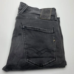 Replay Anbass jeans, - Snygga svarta Replay Anbass jeans med klassisk femficksdesign och diskreta sömmar på bakfickan. Jeansen har en slim passform och är tillverkade i mjukt denimtyg som sitter skönt hela dagen. Perfekta för dig som gillar stilrena och moderna jeans.